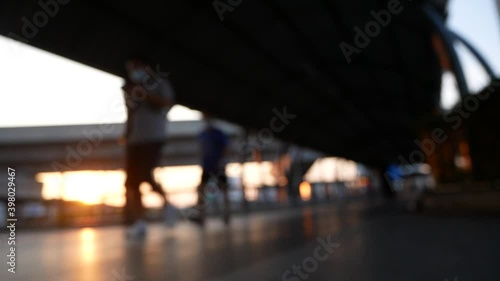 Blurred people walking on walkway with sunset in twilight.