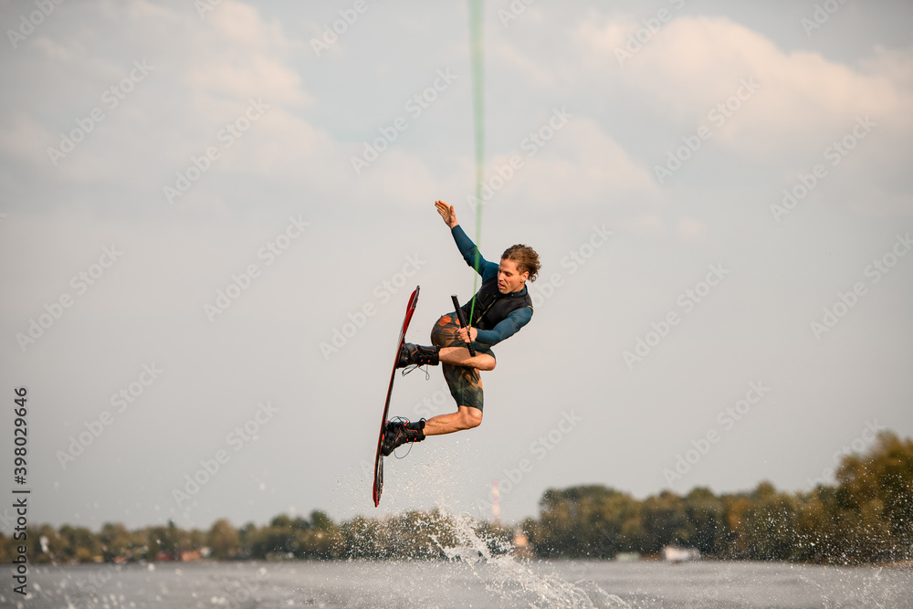 view of athletic male wakeboarder jumping high over river water