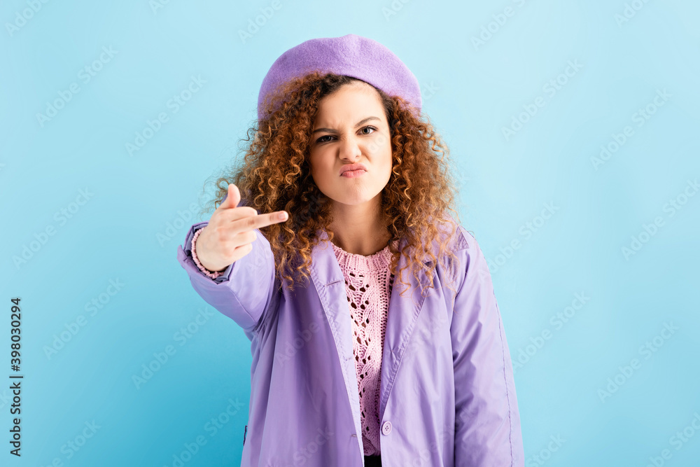 angry woman in beret showing middle finger on blue angry woman in beret showing middle finger on blue