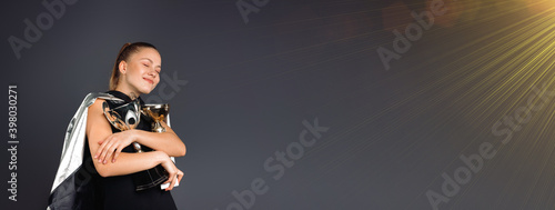 Banner. Businesswoman embrace two champion trophy, young and confident girl, 20s, isolated on gray.
