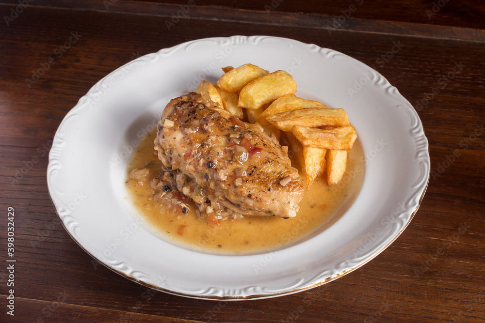 Presentation of a chicken meal with vegetable sauce and potatoes on a white porcelain plate. Kitchen recipes. Presentation of a chicken meal with vegetable sauce and potatoes on a white porcelain plate. Kitchen recipes.