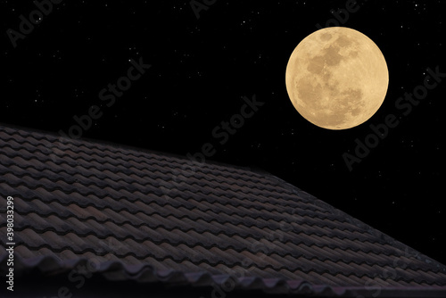 Full moon on the sky over roof tiles.

