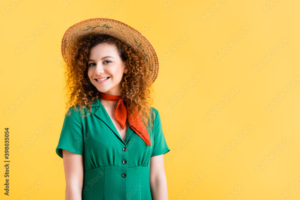 smiling young woman in green dress and straw hat looking at camera isolated on yellow smiling young woman in green dress and straw hat looking at camera isolated on yellow