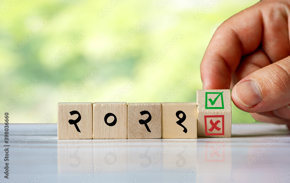 Φωτογραφία hand turns the wooden cube and changes the hindi word (english = 2021) with green positive tick check box and red reject X check box
