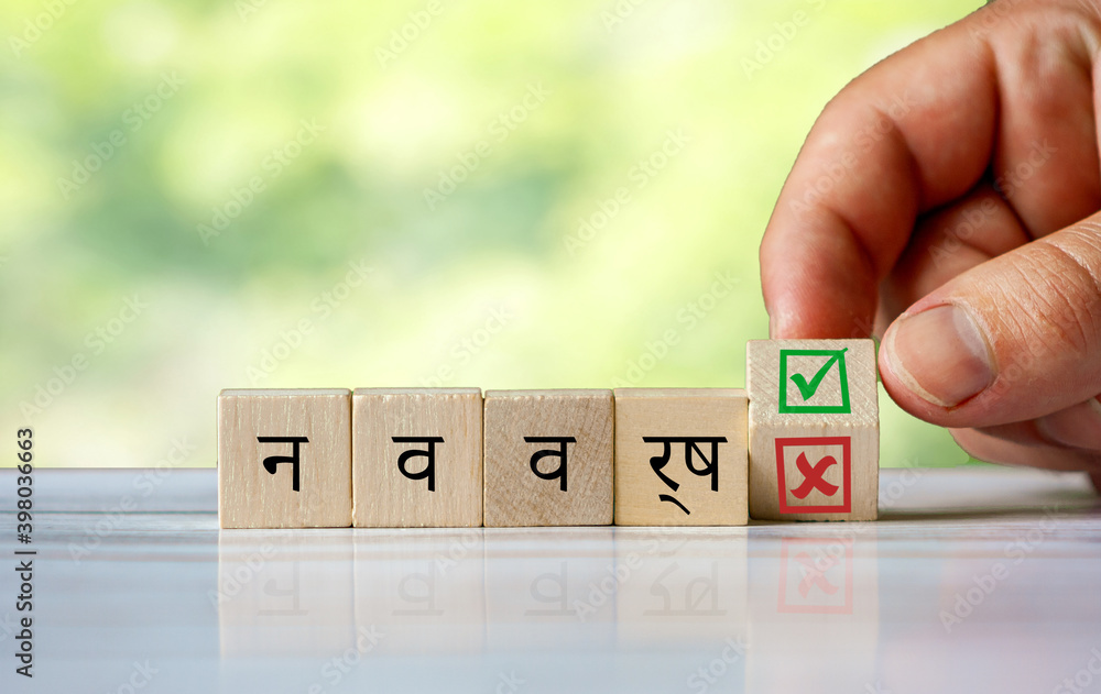 Φωτογραφία hand turns the wooden cube and changes the hindi word (english = new year) with green positive tick check box and red reject X check box