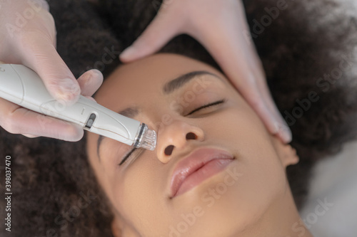Beautician hand holding special apparatus near patient nose