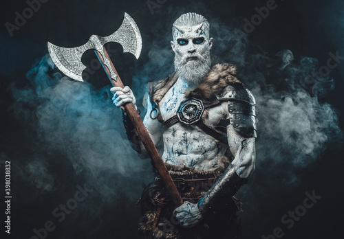 Bringer of the death king with pale skin holding two handed axe and looking down in dark smokey background.
