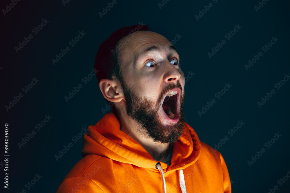 Dumbfounded. Portrait of crazy scared and shocked caucasian man isolated on dark background. Copyspace for ad. Bright facial expression, human emotions concept. Watching horror on TV, cinema.