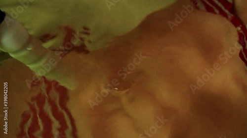Medical procedure hydromassage in the bath. Female hand with a hydromassage, a slender girl in a bikin in the water in the bath.