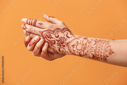 Beautiful female hands with henna tattoo on color background