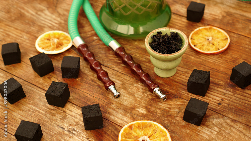 Tobacco in the bowl for hookah on wooden background with coal and dried orange slices Tobacco in the bowl for hookah on wooden background with coal and dried orange slices