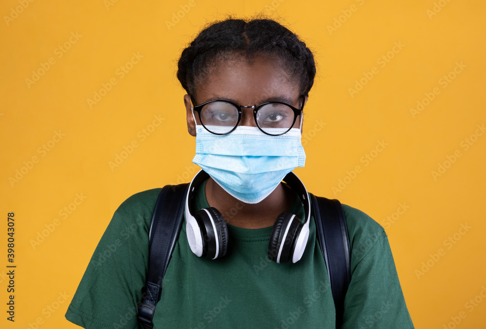 African Student Wearing Protective Face Mask On Yellow Studio Background African Student Wearing Protective Face Mask On Yellow Studio Background