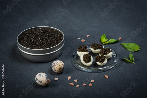 Black caviar of sturgeon in the quail eggs on a dark background. New Year's feast.