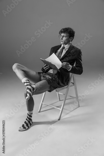 Offers. Young fashionable, stylish man wearing jacket and socks working from home. Fashion during insulation 'cause of coronavirus pandemic. Half business and half home style. Black and white.
