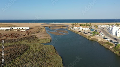 Aerial drone view of Rio Salado flowing next to Conil into the Atlantic ocean through a sand beach in Andalusia