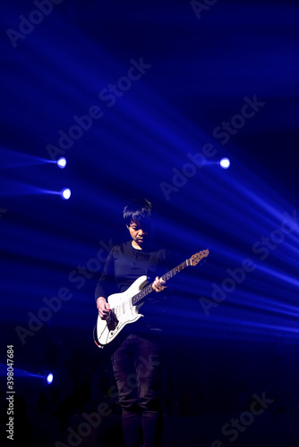 A musician man playing the Guitar on the stage with beautiful blue lighting © Somchai