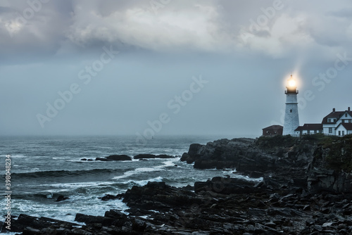 Gloomy gloomy photo of a luminous lighthouse on a rocky shore. Famous lighthouse. Portland. USA. Maine