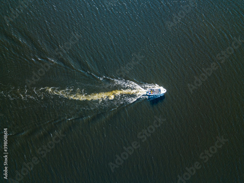 Aerial drone view. The motor boat is sailing along the river. Sunny summer day, small waves. © Sergey
