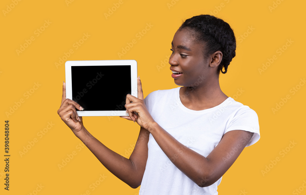 African Woman Showing Digital Tablet Screen Over Yellow Background