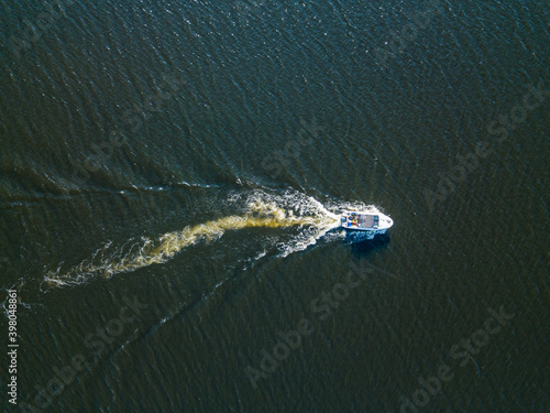 Aerial drone view. The motor boat is sailing along the river. Sunny summer day, small waves. © Sergey