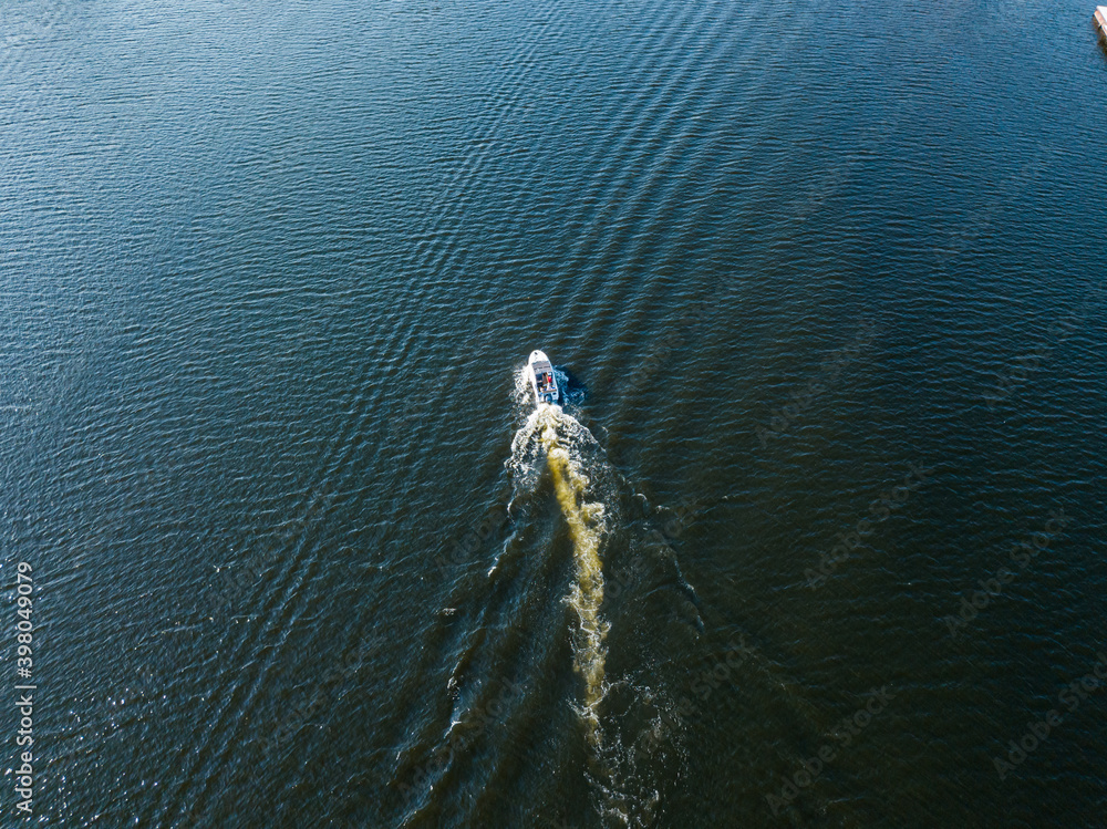 Fototapeta premium Aerial drone view. The motor boat is sailing along the river. Sunny summer day, small waves.