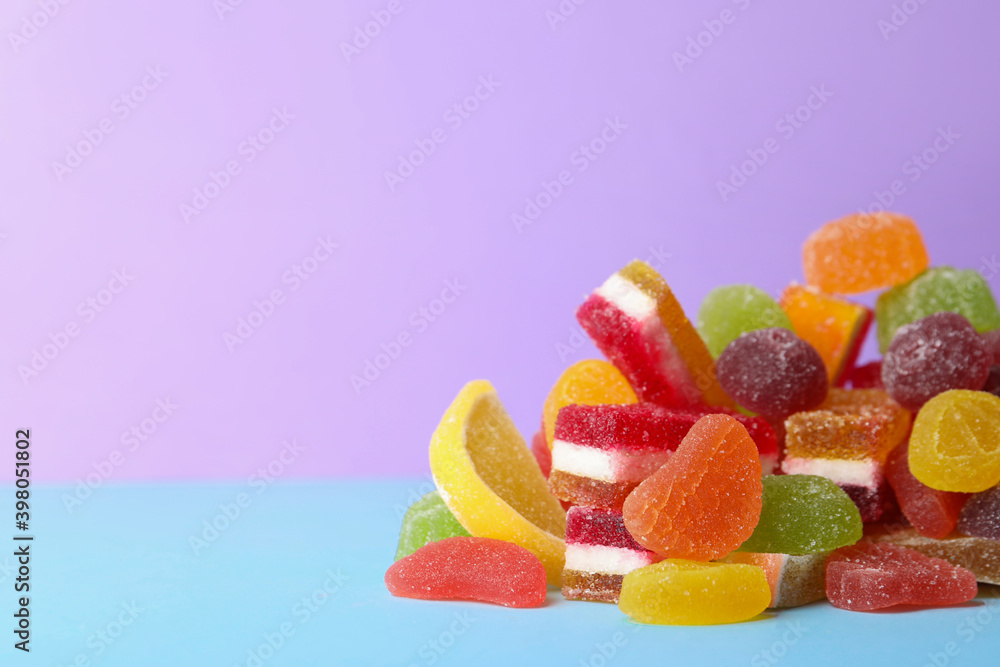 Pile of delicious bright jelly candies on violet background. Space for text