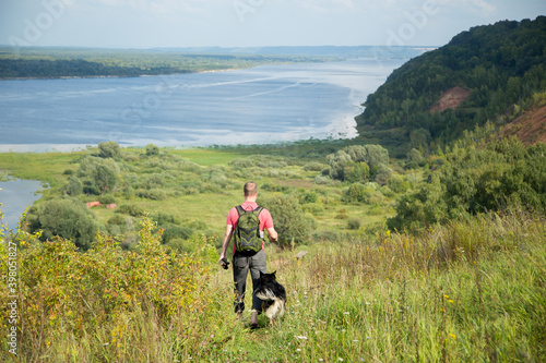 Man travels with dog in summer, trekking on the green hills by Volga river, russian nature, beautiful aerial panoramic view