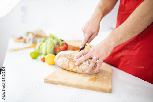 Male hands slicing bread on a cutting board