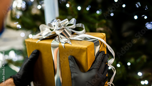 Obraz na płótnie gift - christmas holiday 2020 - handing a gift with gloves w salonie