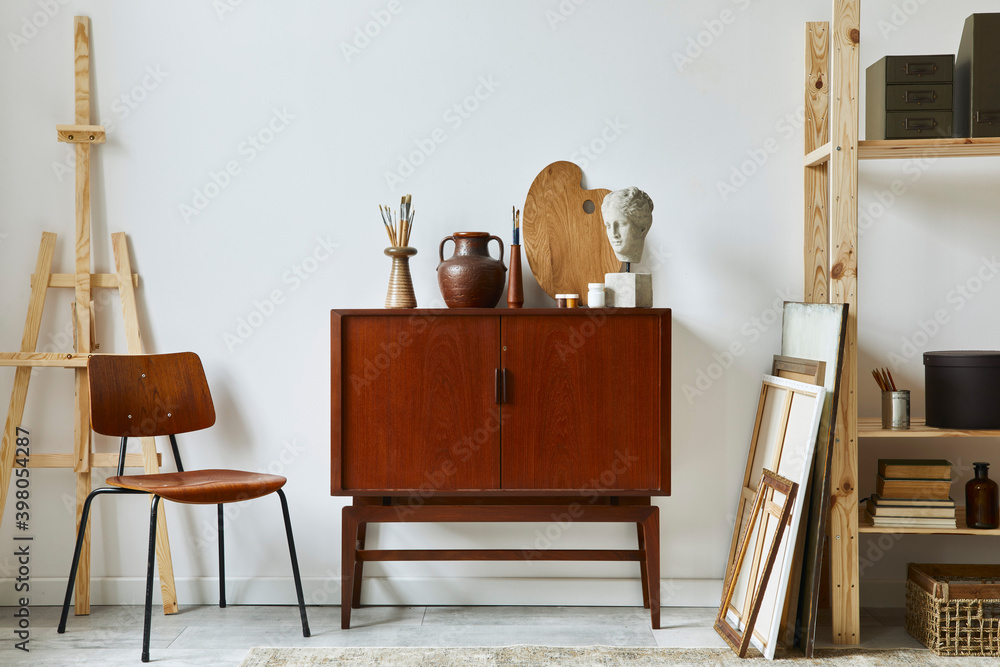 Stylish composition of artist design retro teak commode, chair, bookcase, frames, easel, decoration and elegant personal accessories. Template. Stock Photo Adobe Stock