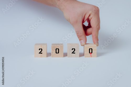Close up of hand completing the year 2020 with symbolic drops of blood on wooden cubes. White background, concept