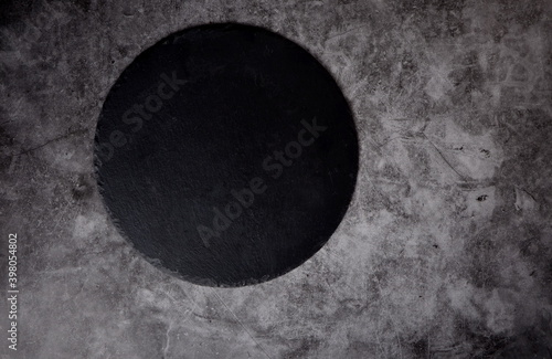 Empty black rustic slate stone plate on dark concrete background, copy space, top view
