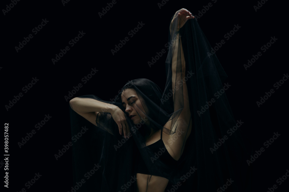 Scared. Graceful classic female ballet dancer isolated on black studio background. Woman in minimalistic black cloth looks graceful, inspired. The grace, artist, movement, action and motion concept.