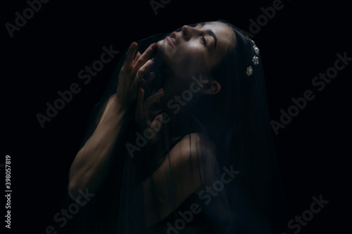 Loving. Graceful classic female ballet dancer isolated on black studio background. Woman in minimalistic black cloth looks graceful, inspired. The grace, artist, movement, action and motion concept.