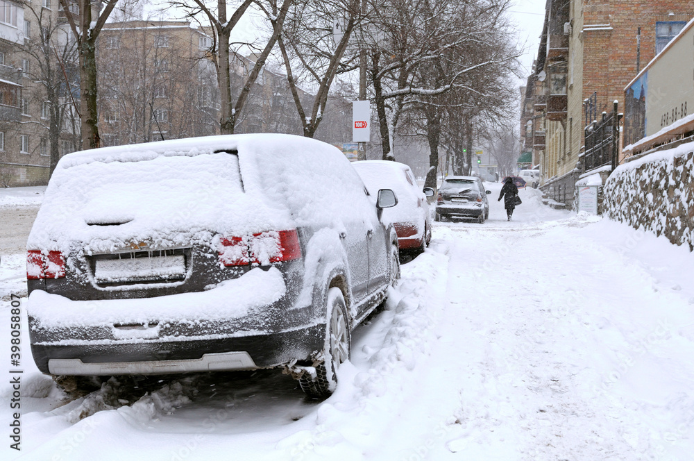 City after blizzard. Cars parked on a street covered with snow. Kyiv, Podil district, Ukraine