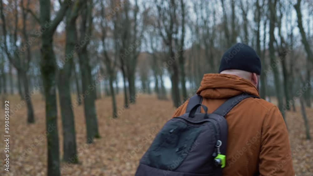 A man walks through the autumn forest. Takes a couple of steps, looks around and leaves A man walks through the autumn forest. Takes a couple of steps, looks around and leaves