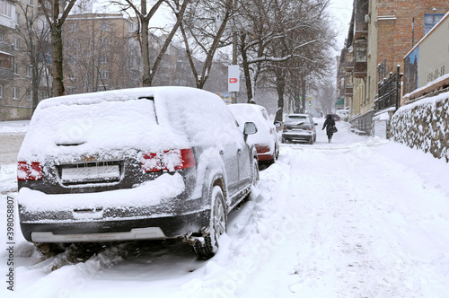 City after blizzard. Cars parked on a street covered with snow. Kyiv, Podil district, Ukraine