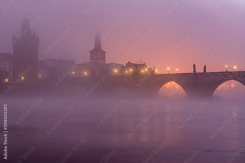 A mysterious autumn dawn at Charles Bridge covered in thick mist in historical center of Prague. 
