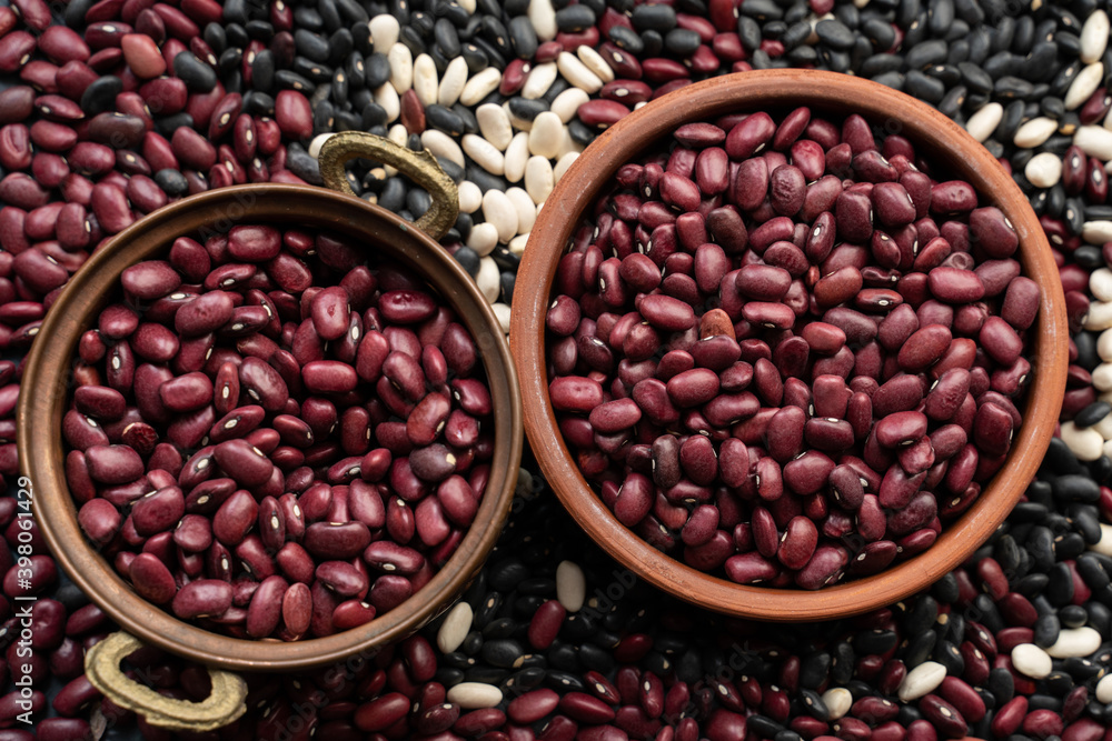 beans in brown ceramic bowl and copper bowl. bowl of beans. black bean, red kidney bean and white bean. navy bean, cannellini bean, white kidney bean. scattered various beans beans in brown ceramic bowl and copper bowl. bowl of beans. black bean, red kidney bean and white bean. navy bean, cannellini bean, white kidney bean. scattered various beans