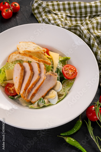 salad with chicken and chips in a white plate on a dark background. Caesar Salad