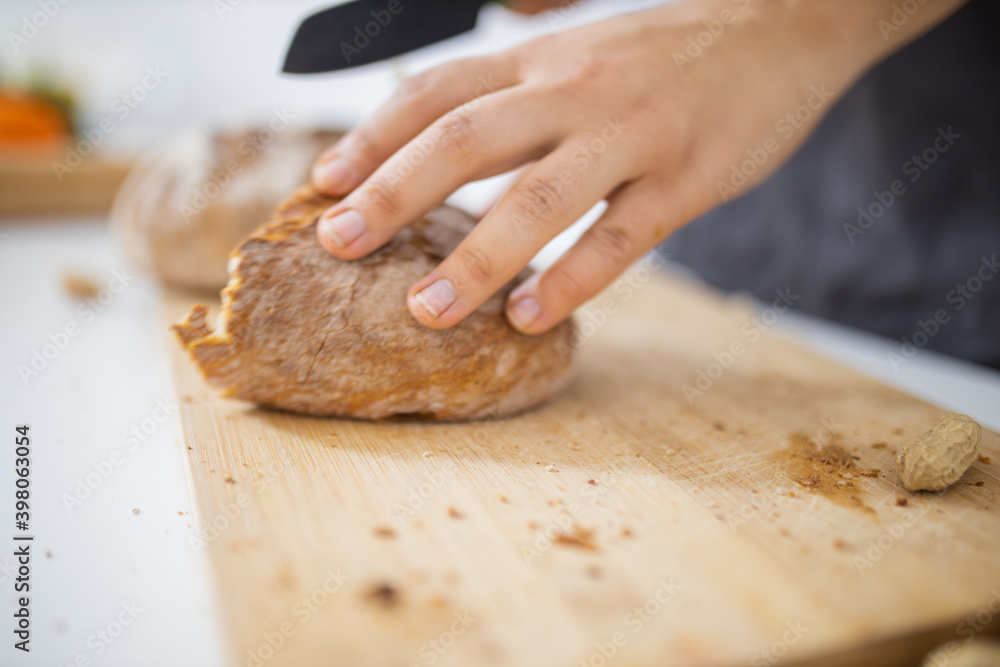 Female hands slicing bread on a cutting board Female hands slicing bread on a cutting board