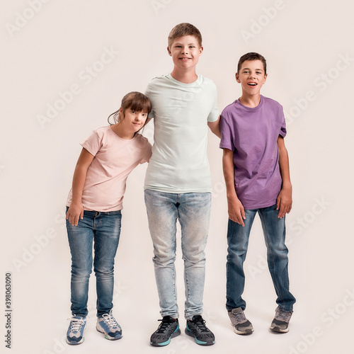 Full length shot of three cheerful teenaged disabled children with Down syndrome and cerebral palsy smiling while standing together isolated over white background © Svitlana
