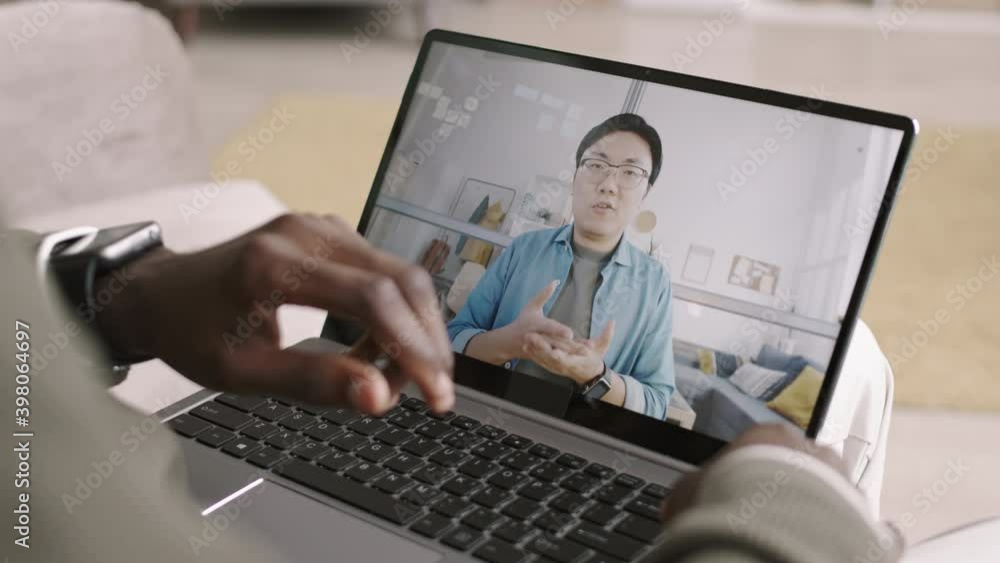 Back view of unrecognizable African-American man wearing smartwatch having video meeting with young Asian businessman. Men comparing time on their smartwatches Back view of unrecognizable African-American man wearing smartwatch having video meeting with young Asian businessman. Men comparing time on their smartwatches