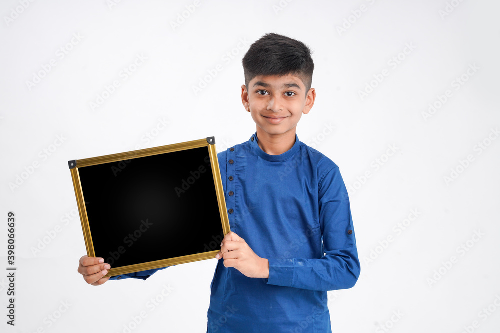 Cute indian little boy showing black board with copy space over white background Cute indian little boy showing black board with copy space over white background