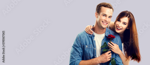 Love, relationship, dating, flirting, romantic concept - portrait picture of happy embracing couple with flower. Over grey background. Copy space for some text.