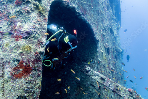 Diver looking out of the hatch in the tower of the sunken ship at the bottom of the Indian ocean photo