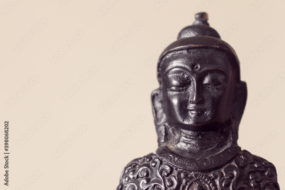 Close-up of a statue of Buddha against Set Sail Champagne color (trend color 2021) background. Copy space.
