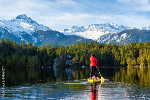 Adventurous Girl Paddle Boarding on Levette Lake with famous Tantalus Mountain Range in the background. Taken in Squamish, North of Vancouver, British Columbia, Canada. © edb3_16