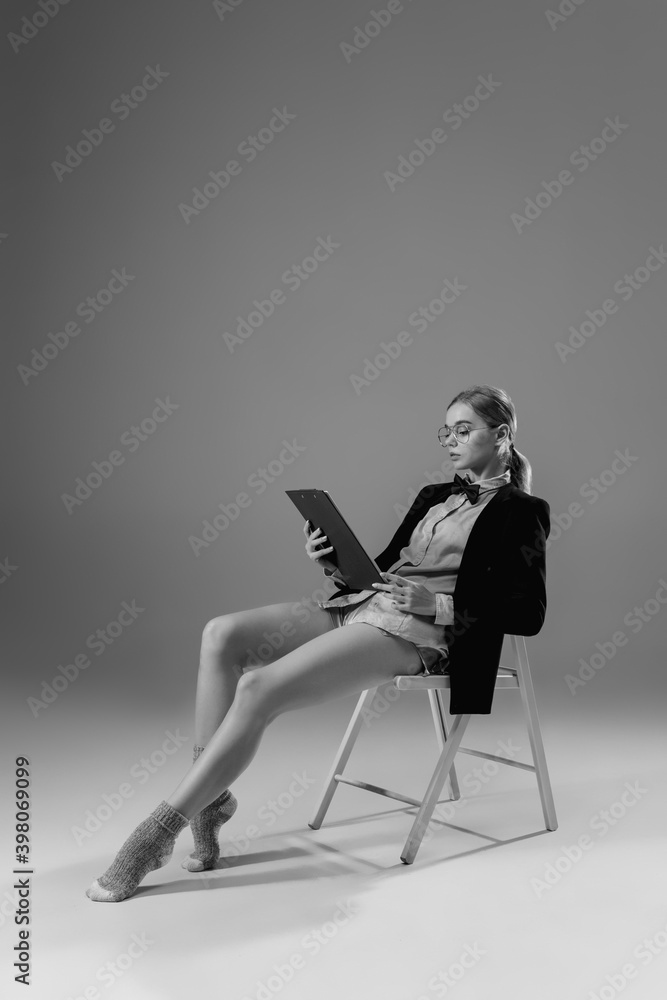 Fototapeta premium Contracts. Young fashionable, stylish woman wearing jacket and socks working from home. Fashion during insulation 'cause of coronavirus pandemic. Half business and half home style. Black and white.