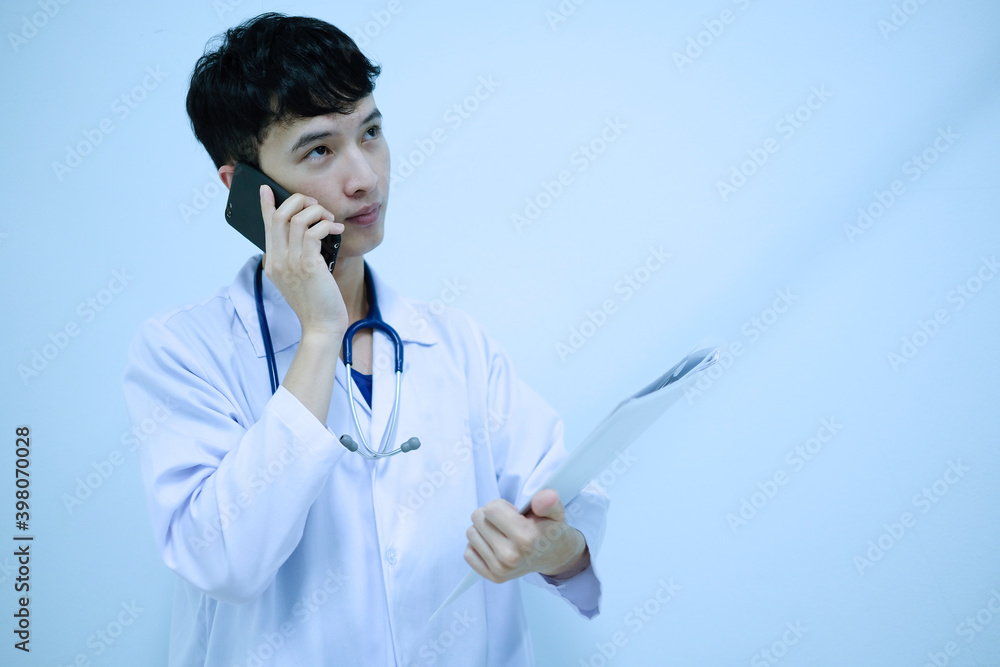 A male doctor talking telephone and holding document file A male doctor talking telephone and holding document file